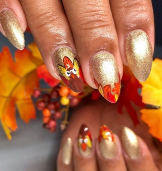 Manicured hands painted with goldcolored nail polish and illustrations of Turkeys