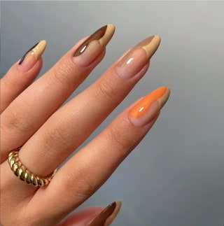 Manicured hand with swirls painted in orange beige and brown