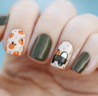 Manicured hand with green nail polish illustrations of pumpkins and a pumpkin in a green truck