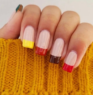 Manicured hand with tips painted in red brown and yellow.