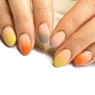 Ombre manicure in yellow orange and gray with gold cuticles