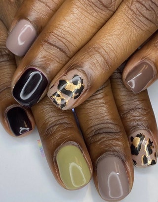 Manicured nails painted in black green spots and dark brown