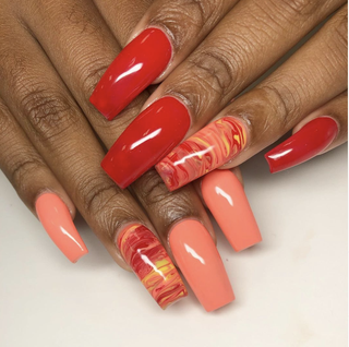 Manicured nails painted in a marblelike design along with some of the nails painted in orange and red.